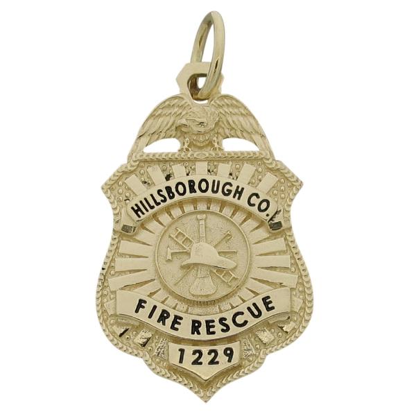 Custom Hillsborough FL Fire Rescue badge pendant in 14k yellow gold with fire scramble center and black enamel.