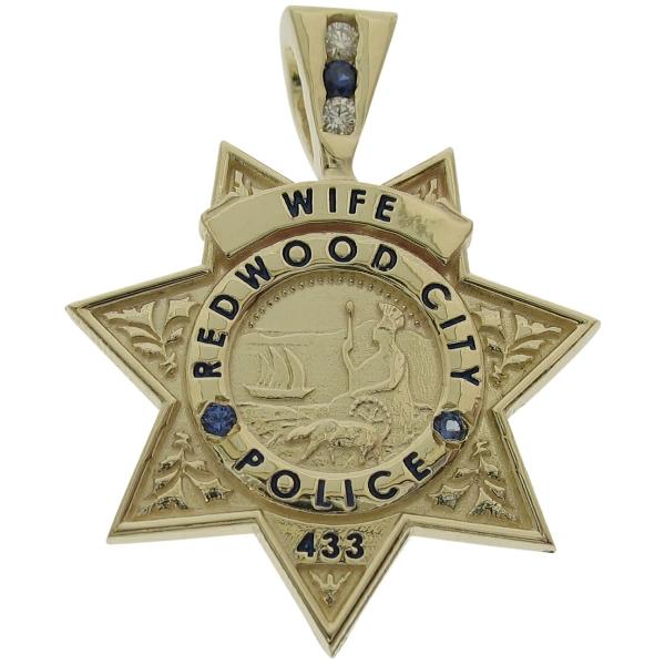 Custom Redwood CA Police Officer badge pendant in 10k yellow gold with optional 3-stone bail featuring 2-diamonds and 1-blue sapphire. Two blue sapphires bead set in California seal bezel with black enamel text.