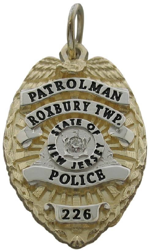 Custom Roxbury Twp. NJ Police Patrolman badge pendant in 10k yellow gold with rhodium plate ribbons and center seal, black enamel text, and optional 0.03 ct. round brilliant diamond center stone.
